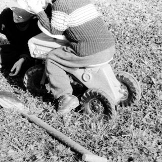 A child plays with a cat on grass.