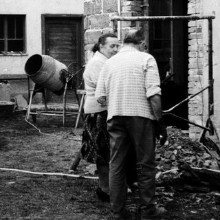 Construction workers mixing concrete outdoors near a building.