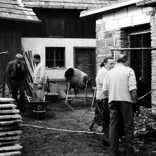 Construction workers mixing concrete outdoors near a building.