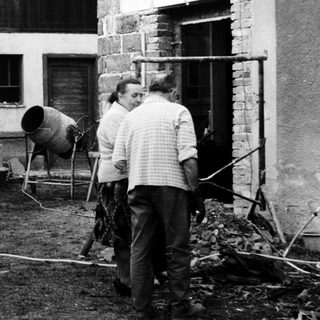 Construction workers mixing concrete outdoors near a building.