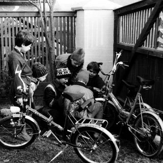 Five children with bicycles in a backyard.