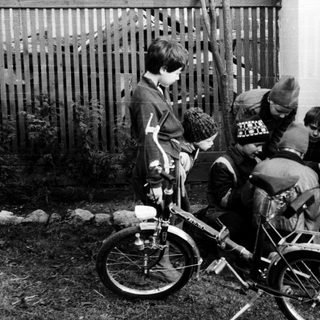 Five children with bicycles in a backyard.