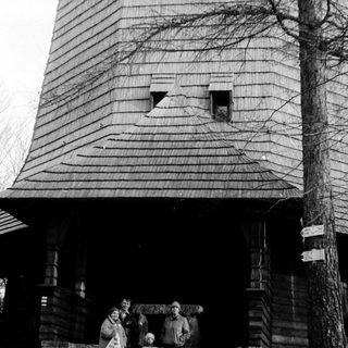 Family posing outside historic wooden windmill.