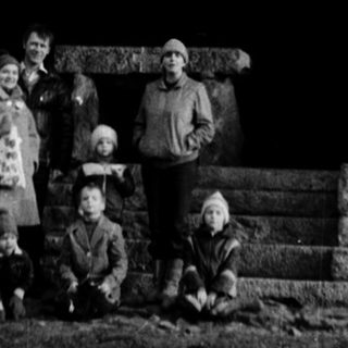 Family posing outside historic wooden windmill.