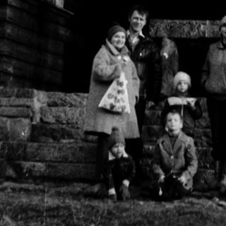Family posing outside historic wooden windmill.