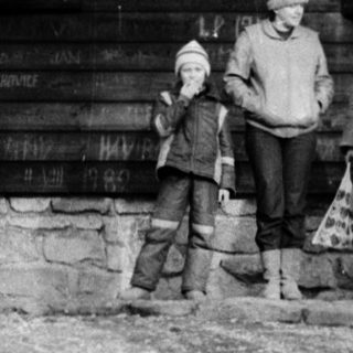 Family posing outdoors near rustic wooden cabin.