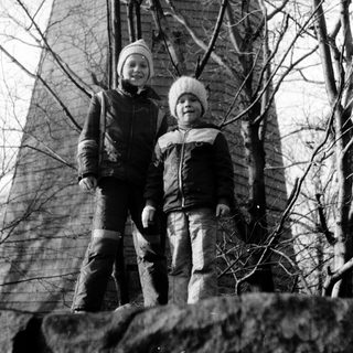 Two people standing outdoors near tall stone tower.
