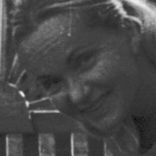 Woman gardening near a fence.