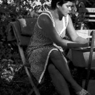 Woman reading outdoors on garden chair.