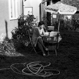 Woman reading outdoors on garden chair.