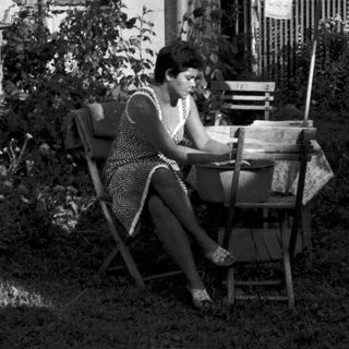 Woman reading outdoors on garden chair.