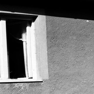 Person reading outdoors on folding chair near house.