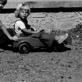 Two children playing with toy wagon outdoors.