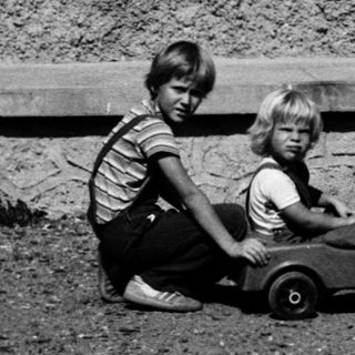 Two children playing with toy wagon outdoors.