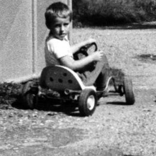 Children playing with toy cars on gravel path.