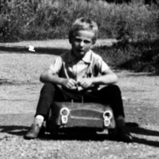 Children playing with toy cars on gravel path.