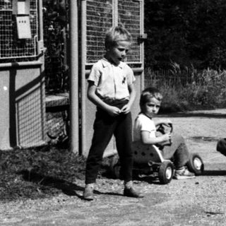 Children playing with scooters near public phone booths.