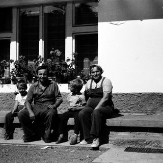 Family posing together outdoors near a building.