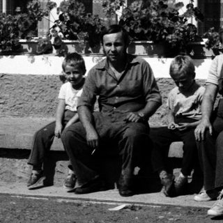 Family posing outside a house in vintage clothing.