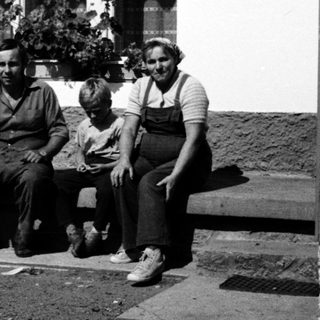 Family posing outside a house in vintage clothing.
