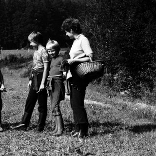 Family foraging berries in rural countryside.