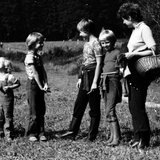 Family foraging berries in rural countryside.