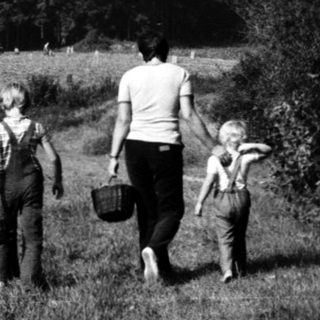 Family walking through rural countryside with basket.