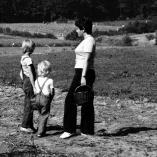 Family hiking near forested hilltop.