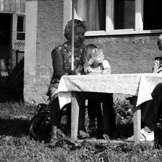 Family dining outdoors under patio umbrella.