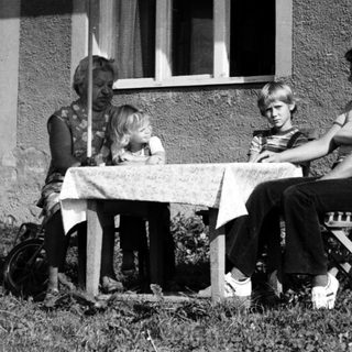 Family dining outdoors under patio umbrella.