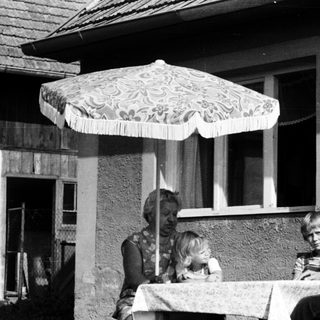 Family dining outdoors under patio umbrella.