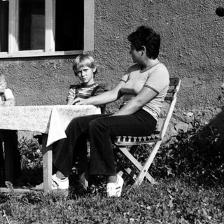 Family dining outdoors under patio umbrella.