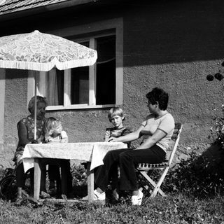 Family dining outdoors under patio umbrella.