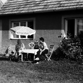 Family relaxing outdoors near house.