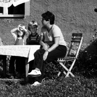 Family relaxing outdoors near house.