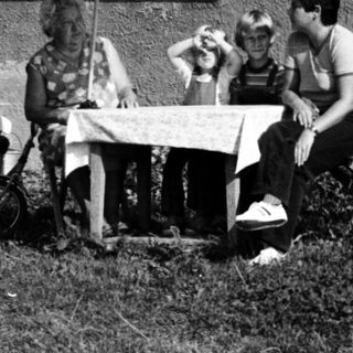 Family relaxing outdoors near house.