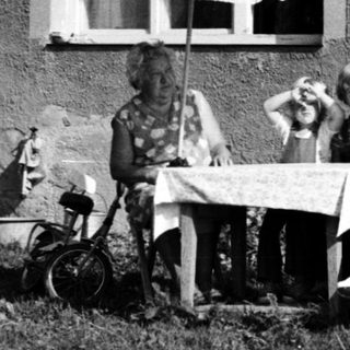 Family relaxing outdoors near house.