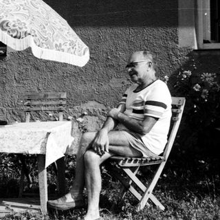 Two people sitting outdoors under umbrella, enjoying conversation.