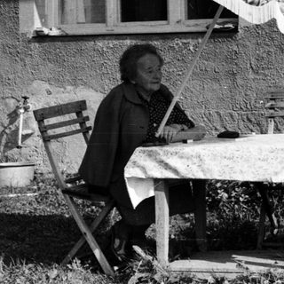 Two people sitting outdoors under umbrella, enjoying conversation.