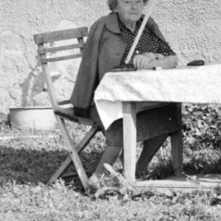 A person sitting on a folding chair outside a house.