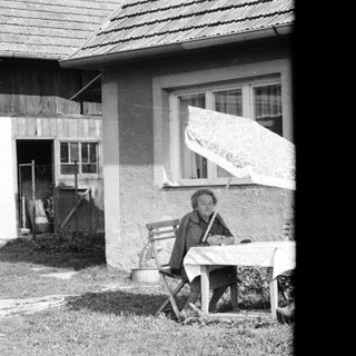 A person sitting on a folding chair outside a house.
