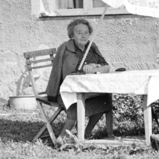A person sitting on a folding chair outside a house.