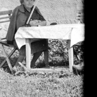 A person sitting on a folding chair outside a house.