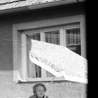 A person sitting on a folding chair outside a house.