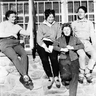 Four people sitting together outdoors in winter attire.