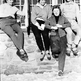 Four people sitting together outdoors in winter attire.