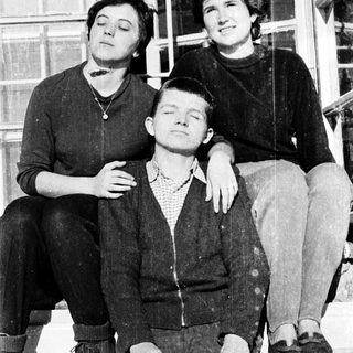 Three people posing together on stairs, mid-20th century.
