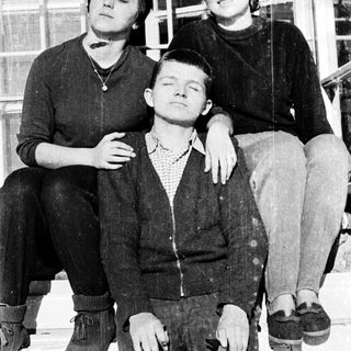 Three people posing together on stairs, mid-20th century.