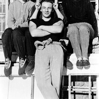 Four people posing together outdoors on a ledge.
