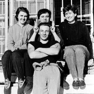 Four people posing together outdoors on a ledge.